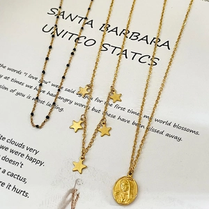 Collier multi-rangs doré vintage avec breloques étoiles et pendentif Maria sur papier