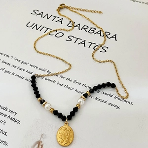 Collana artigianale di perle nere con ciondolo a moneta d'oro su un libro di poesie