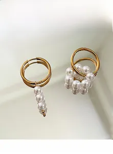 Detail of gold geometric earrings featuring asymmetric white pearl clusters and reflection