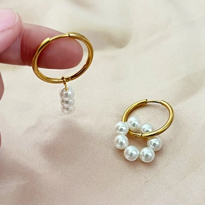 Vintage geometric titanium steel earrings with white pearls on a soft beige cloth background