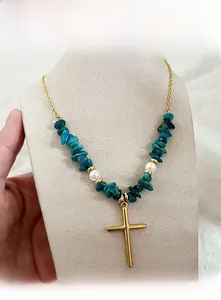 Détail d'un collier croix doré avec des pierres bleues et perles sur un mannequin