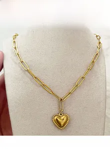 Dettaglio della collana a catena a graffetta dorata con ciondolo a cuore su manichino
