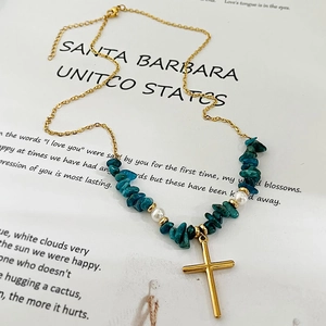 Collier bohème avec pendentif croix, pierres turquoise et perles blanches sur magazine