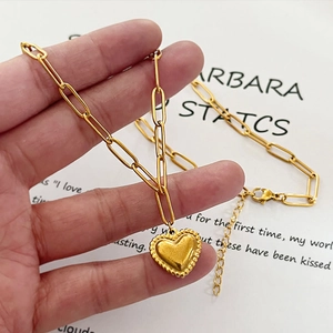 Collana a catena a graffetta dorata con ciondolo a cuore tenuto da una mano