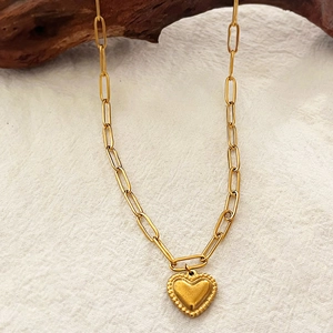 Collana con ciondolo a cuore dorato e catena a graffetta su espositore in legno