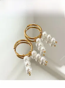 Detailed view of elegant gold hoop earrings with white pearl beaded drop pendants