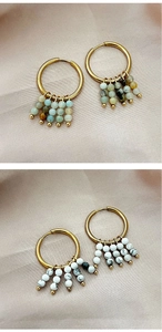 Détail de boucles d'oreilles dorées 18k avec pierres naturelles colorées et perles