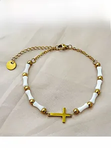 Detail of beaded cross bracelet featuring white ceramic beads and gold-plated chain
