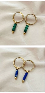 Detail of gold hoop earrings with green malachite and blue stone cylinder pendants