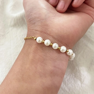 Bracelet élégant en perles dorées avec sept perles blanches et chaîne fine au poignet