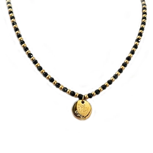 Collier artisanal perles noires et dorées avec pendentif rond à motif floral chic