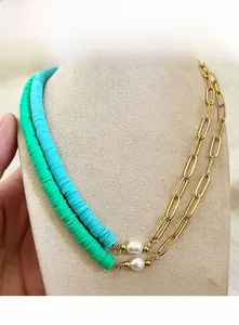 Close-up of layered necklaces with turquoise clay beads, pearls, and golden paperclip chain