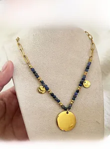 Detail of beaded necklace featuring blue natural stones and gold brushed circular pendants