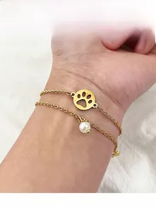 Detail eines böhmischen Gold-Doppelkettenarmband mit Stern, Perle und Pfotenabdruck-Anhänger