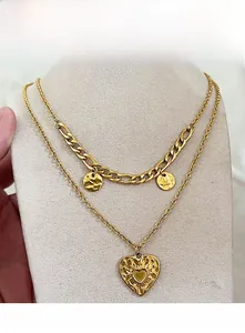 Close-up of vintage gold double-layer necklace with embossed heart and coin pendants