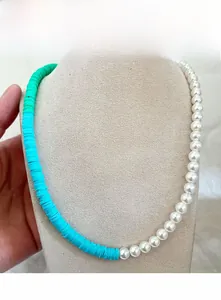 Détail d'un collier asymétrique avec perles blanches et perles en argile colorées sur buste