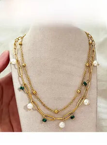 Détail d'un collier doré à double épaisseur avec perles de malachite verte et blanches