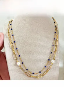 Détail d'un collier double épaisseur en titane plaqué or avec perles et perles bleues sur buste