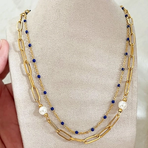 Collier double rang doré avec perles blanches et perles bleues sur un buste de bijoux