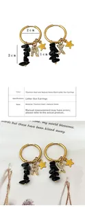 Detail view of 18k gold star earrings with natural black stone and letter pendants