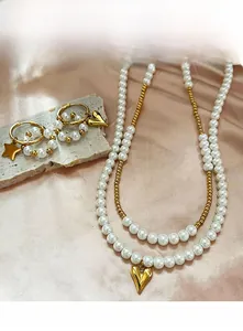 Detail of layered pearl necklace with gold heart pendant and matching star earrings