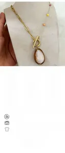 Detail of gold chain necklace featuring colorful beads and teardrop shell pendant