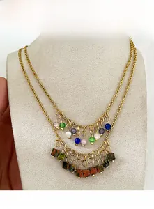 Detail of beaded tassel necklace featuring colorful cat's eye stones and gold chain layers