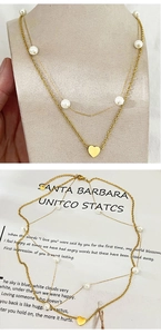 Gros plan du collier double épaisseur doré avec pendentif cœur et perles blanches