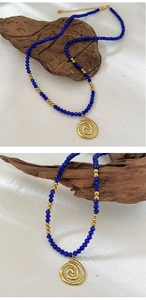 Detail of bohemian beaded necklace featuring royal blue stones and golden spiral pendant