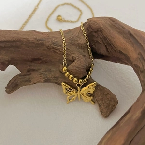 Elegante goldene Schmetterlingskette mit runden Perlen an einer feinen Gliederkette