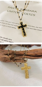 Dettaglio della collana a doppia croce in smalto nero con catena a sfere dorata