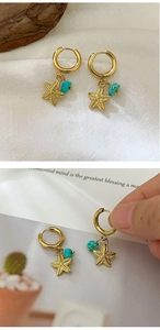 Detailed shot of gold hoop earrings with starfish pendants and turquoise stone accents