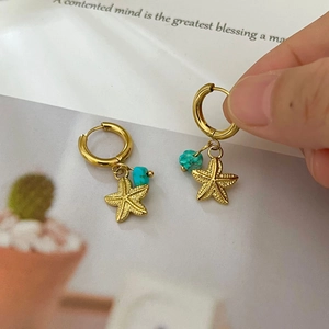 Golden starfish and turquoise stone drop earrings on minimalist background for women