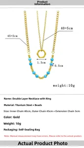 Detail showing dual-layer gold titanium steel necklace with blue bead and ring pendant