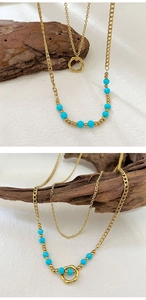 Macro detail of layered 18K gold-plated necklace with turquoise beads and round pendant