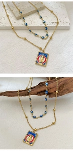 Detail of gold double-layered necklace with blue evil eye beads and religious pendant