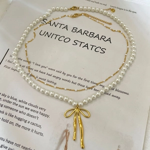 Collier double épaisseur en perles avec pendentif nœud doré sur fond vintage
