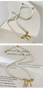Détail du pendentif nœud plaqué or 18k sur collier de perles blanches fait à la main