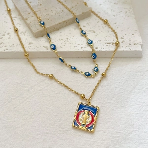 Double-layered evil eye pendant necklace and gold portrait charm on stone surface