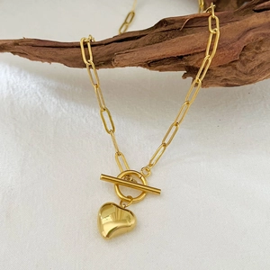 Collier à pendentif cœur doré avec chaîne trombone et fermoir OT sur fond de bois
