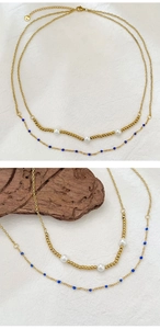 Detail of gold double-layer necklace featuring white pearls and tiny blue beads