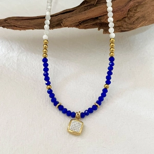 Beaded natural stone necklace with square rhinestone pendant hanging on a rustic wood branch