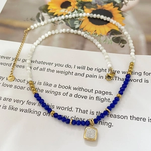 Handmade beaded necklace with blue stones and a gold square rhinestone pendant on a card