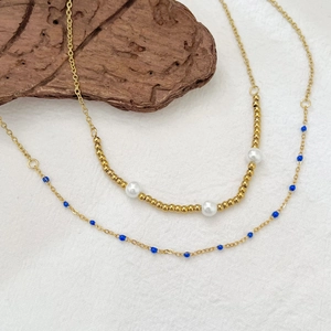 Double-layered gold titanium necklace featuring white pearls and blue bead accents