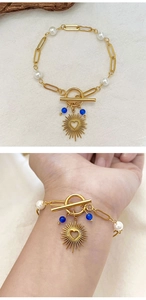 Detail of 18K gold-plated pearl bracelet with heart charm and OT clasp on a wrist