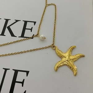 Golden starfish pendant necklace with a white pearl and textured finish on a cross chain