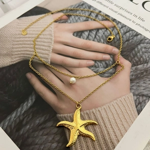 Double-layered gold starfish pendant necklace with pearl on a lifestyle background