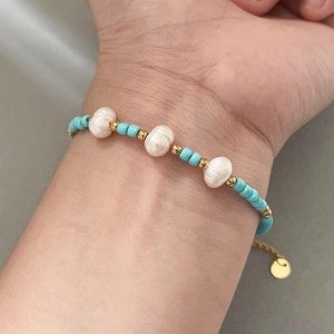 Handmade necklace with blue turquoise beads, freshwater pearls and gold accents worn on wrist