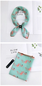 Detail of mint green neck scarf with pink crane pattern and black leather ring buckle