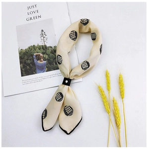 Detail of beige dot scarf with black leather ring buckle and minimalist props